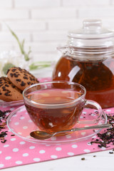 Teapot and cup of tea on table on brick wall background