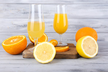 glasses of juice with fresh fruits on grey wooden table