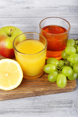 glasses of juice with fresh fruits on grey wooden table