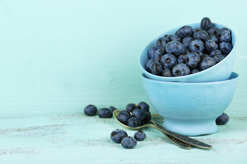 Tasty ripe blueberries in cups, on wooden table