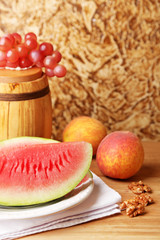 Composition of ripe watermelon, fruits and wooden barrel