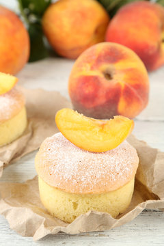 Tasty mini cake with fresh peach, on wooden table