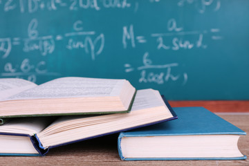 Books on wooden table on blackboard background