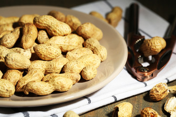 Peanuts on plate, on wooden background