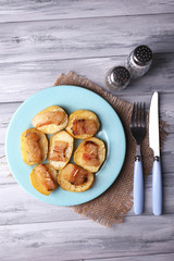 Baked potato with bacon on plate, on wooden background