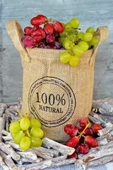 Fotobehang Natuurlijke tros rode en groene druiven in jute zak © trinetuzun