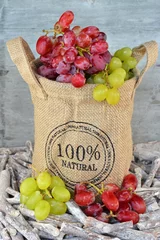 Tapeten Natuurlijke tros rode en groene druiven in jute zak © trinetuzun