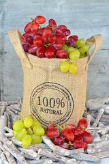 Tapeten Natuurlijke tros rode en groene druiven in jute zak © trinetuzun