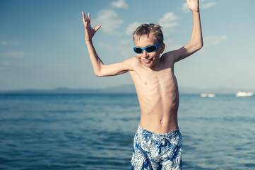 Funny little child playing in sea splashing water and jumping. 