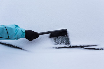 Woman cleaning snow from the car
