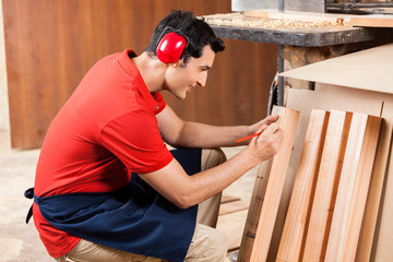 Carpenter Marking On Plank With Pencil