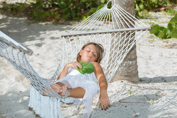 tired little girl lying and sleeping on hammock in garden