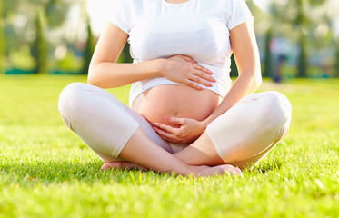 belly of pregnant woman in summer park