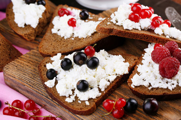 Obraz na płótnie Canvas Bread with cottage cheese and berries on wooden board close-up