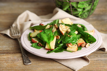 Green salad with apples, walnuts and cheese on wooden