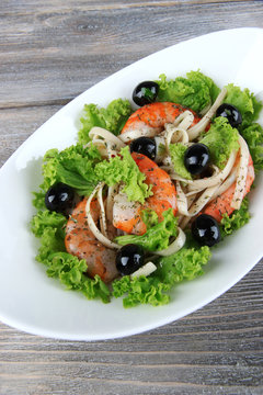 Fresh prawns with spaghetti, olives and lettuce in a white oval