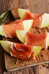 Delicious melon with prosciutto on table close-up