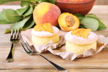 Tasty mini cakes with fresh peach, on wooden table