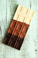 Milk chocolate bar on color wooden background