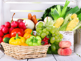 Vegetables in crate and in basket on white wooden box