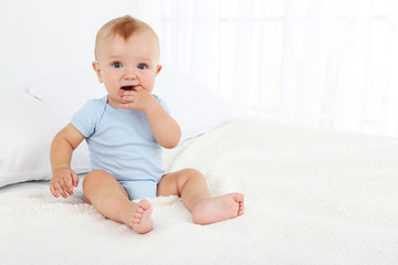 Cute baby boy on bed in room