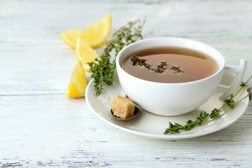 Cup of tasty herbal tea with thyme and lemon on wooden table