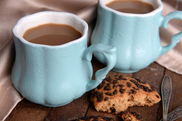 Cups of coffee with cookies and napkin on wooden table
