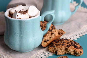 Cups of coffee with marshmallow and cookies on wooden table