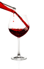 Red wine poured in a glass isolated on white