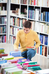 Young man looking at the books in a library.