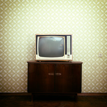 Retro tv with wooden case in room with vintage wallpaper and par