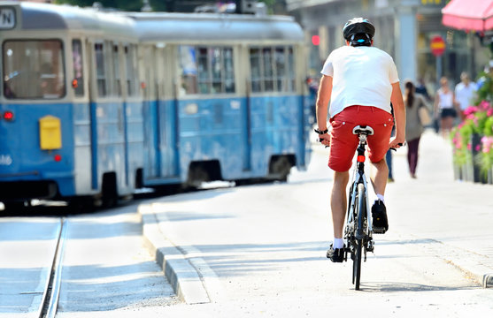Bike commuter and tram in sunlit city