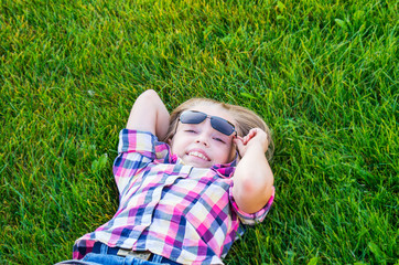 Fototapeta premium Beautiful little girl lying in fresh green grass