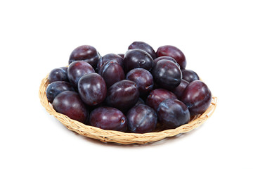 Fresh plums in a wooden basket on white background.