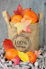 Tapeten Jute zak met mandarijnen en herfstbladeren © trinetuzun