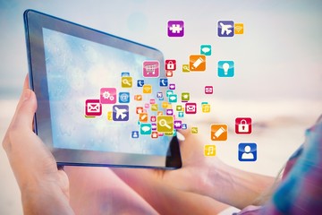 Woman sitting on beach in deck chair using tablet