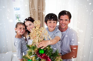 Happy little kid decorating a christmas tree with his family