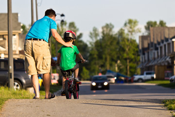 Father helping his child ride their bicycle