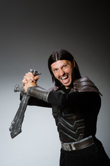 Angry knight with sword against dark background