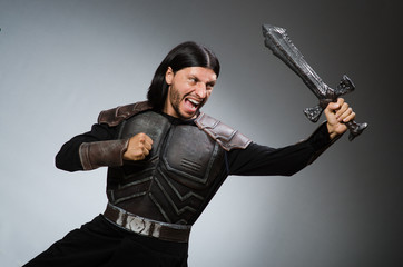 Angry knight with sword against dark background