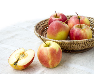Small gala apple and half in basket on sack background.