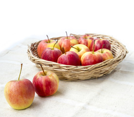 Small gala apple in basket on sack over white.