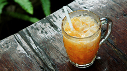 Iced tea with milk on wooden table (Thai beverage)