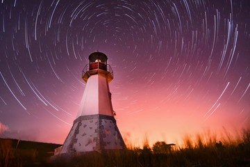 lighthouse with night sky at background stars trails - 70725561