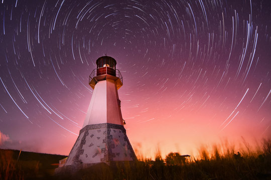 Lighthouse With Night Sky At Background Stars Trails