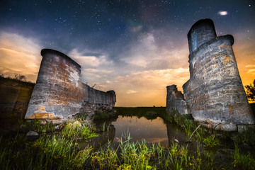 Old night castle wall ruins on lake reflections with stars sky a - 70725997