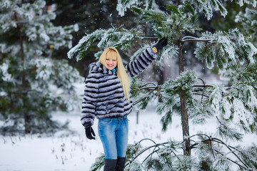Beautiful blonde girl in a snowy forest. fresh air. needles