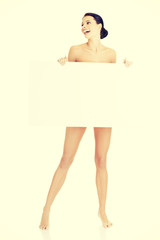 Sexy naked brunette holding empty board