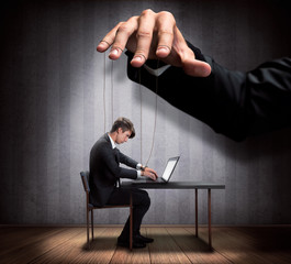 Businessman's hand controlling a worker marionette