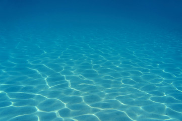 Fototapeta na wymiar Ripples of sunlight underwater on sandy seabed